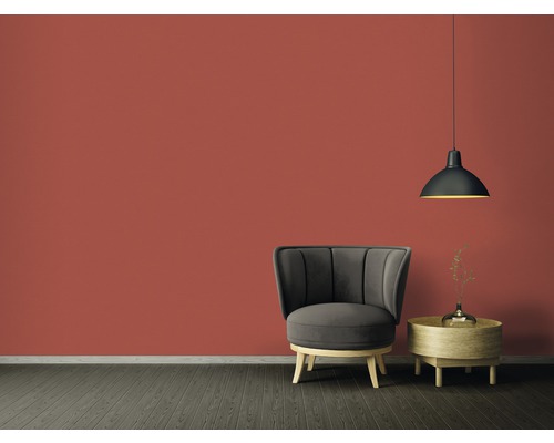 Vardagsrum med fåtölj, sidobord och hänglampa framför en färgad vägg