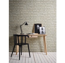 Arbetsrum med skrivbord, skrivbordslampa och stol framför en vägg med tegelstapeter