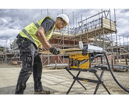 En byggnadsarbetare använder en bordssåg på en byggarbetsplats.