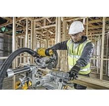 En arbetare använder en DeWalt geringssåg på en byggarbetsplats för att såga en träplanka.