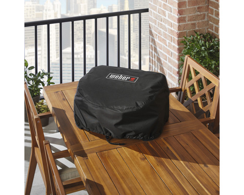 Svart Weber grillskydd på ett träbord