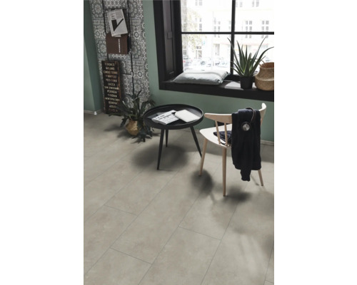 Vardagsrum med ljusgrått golv i kakeloptik, bord, stol och fönster