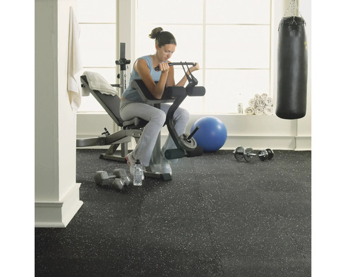 Gym med kvinna som tränar på en hantelbänk på ett gummigolv