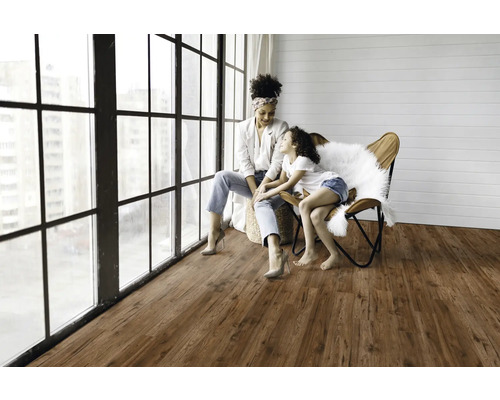 Ljust rum med trägolv, stort fönsterparti och mamma med barn