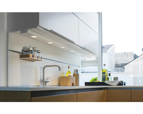 Köksscen med diskho, blandare, belysning och köksredskap.