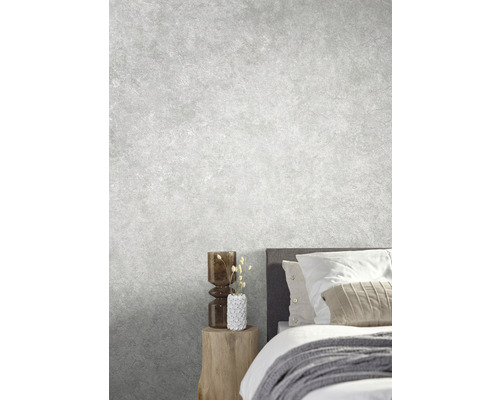 Ljust sovrum med säng, nattduksbord och dekorativa föremål mot en grå vägg