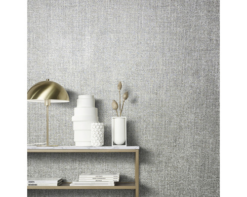 Närbild av en vägg med textil tapet och ett bord med dekoration
