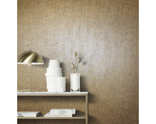 Närbild av en guldfärgad textiltapet med bord, lampa och dekoration