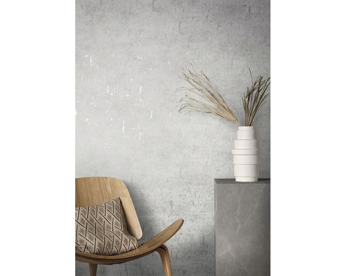 Dekorativ interiör med trästol, kudde, vas och torkade blommor på en sockel.