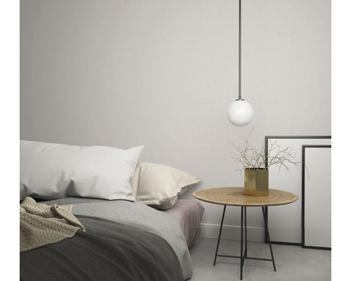 Ljust sovrum med säng, sängbord, sfärisk lampa, vas och fotoramar