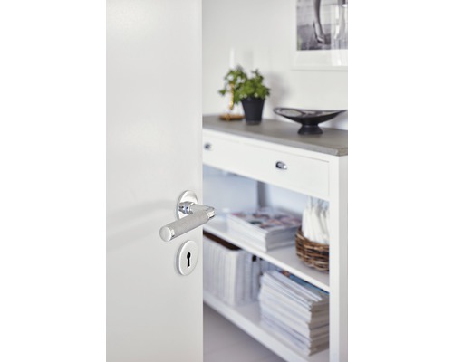 Öppen vit dörr med dörrhandtag och nyckelhål framför vit hylla