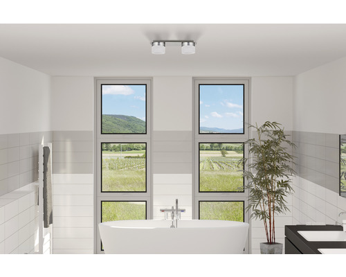 Ljust badrum med fristående badkar, handdukstork, två fönster med utsikt över landskapet och taklampa