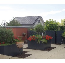 Terrass med planterade blomlådor, trädgårdshus och solcellsanläggning på taket