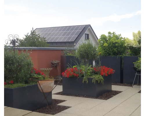 Terrass med planterade blomlådor, trädgårdshus och solcellsanläggning på taket