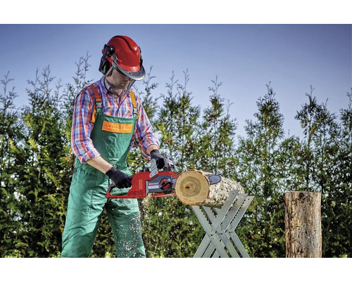 En person sågar en bit trä på en sågbock med en elektrisk motorsåg.