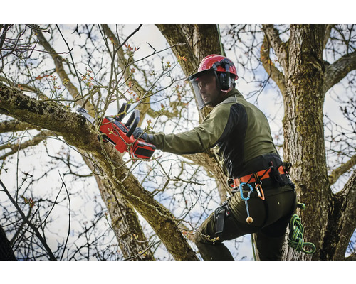 Trädvårdare med hjälm och skyddskläder som sågar en gren med en batteridriven motorsåg.
