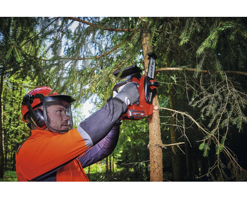 En person med säkerhetsutrustning använder en sladdlös motorsåg för att kapa en trädgren.