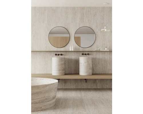 Ljust badrum med dubbla handfat i natursten, runda speglar och matchande badkar.