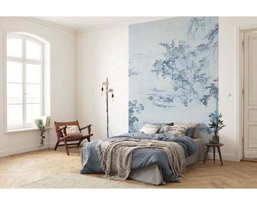 Sovrum med blåmönstrad fototapet, säng, läslampa och trästol