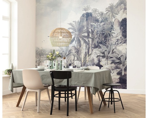 Matsal med matbord, stolar, hänglampa i rotting och tropisk fototapet.