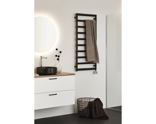 Ljust badrum med tvättställ, spegel, handdukstork och tvättkorg.