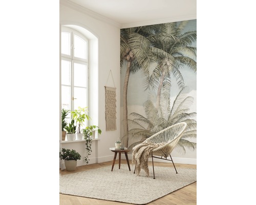 Ljust rum med fönster, palmväggmålning, matta, fåtölj och sidobord
