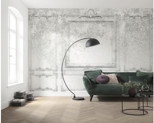 Ljust vardagsrum med dekorativ ramtapet, soffa, golvlampa och trägolv