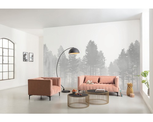 Vardagsrum med soffa, fåtölj, golvlampa och soffbord framför en fototapet med skogsmotiv.