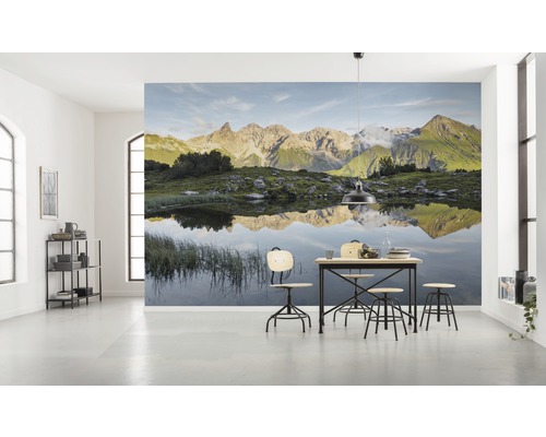 Ljust rum med fotovägg berglandskap och matbord med stolar
