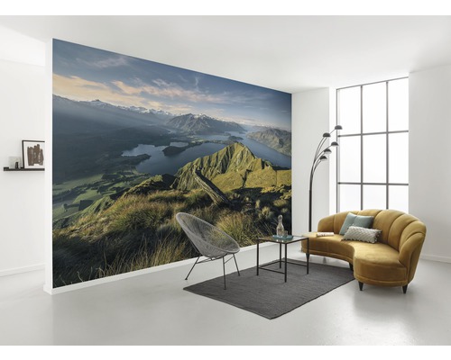Vardagsrum med fototapet bergslandskap, soffa, fåtölj och matta