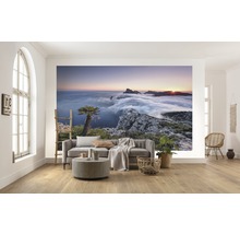 Vardagsrum med fototapet av ett bergslandskap i soluppgången ovanför molnen