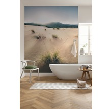 Modernt badrum med badkar, stol, matta och fototapet med motiv av sanddyner