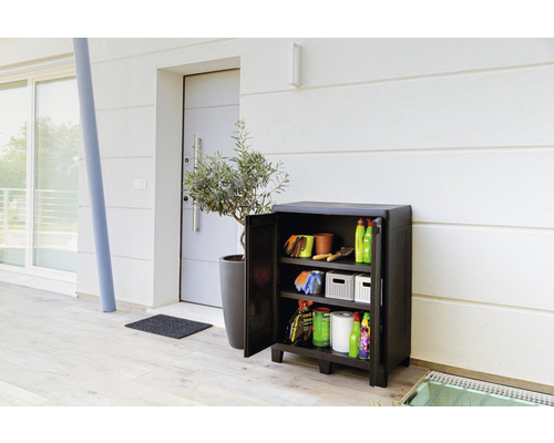 Trädgårdsskåp med öppen dörr, fyllt med trädgårdsredskap framför ett hus