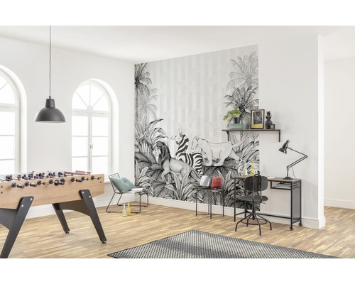 Ljust vardagsrum med en fotovägg med djungelmotiv, bordsfotboll och skrivbord