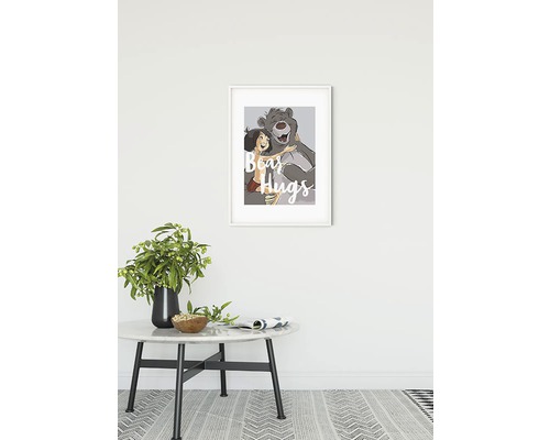 "Dekorativ bild med Mowgli och Baloo björnen med texten ""Bear Hugs"" i en vit ram ovanför ett bord"