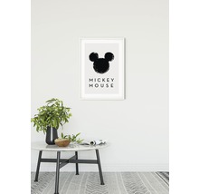 Dekorativ inramad bild med Mickey Mouse-motiv ovanför ett bord med vas och skål