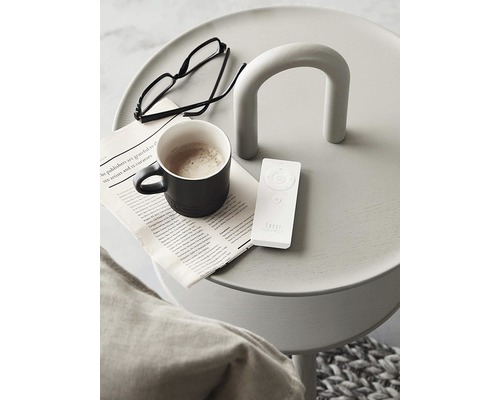 Dekorativt sidobord med tidning, glasögon, kaffekopp och fjärrkontroll