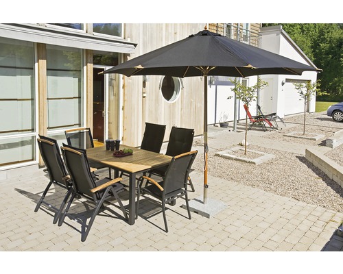 Trädgårdsscen med matbord, stolar och parasoll på en terrass.