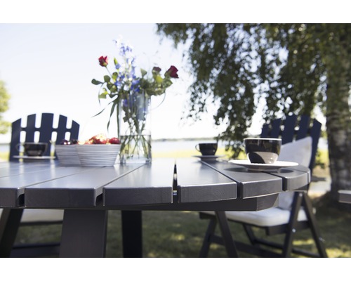 Närbild av ett trädgårdsbord med stolar, porslin och blommor på en gräsmatta