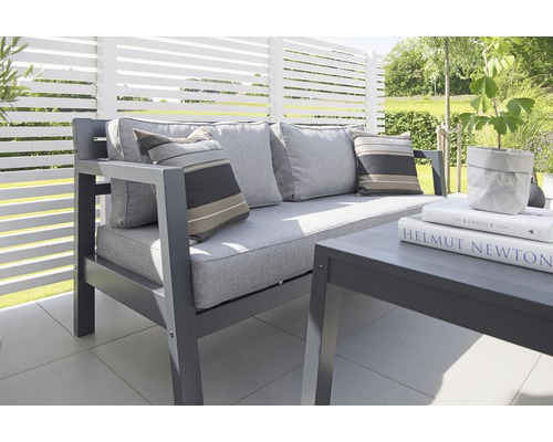 Trädgårdsmöbelgrupp med soffa, kuddar och bord på en terrass