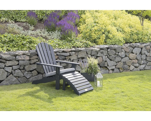 Trädgårdsscen med Adirondackstol, fotpall och blommor i bakgrunden