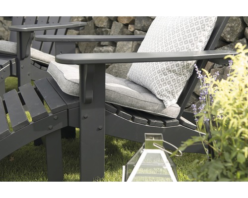 Närbild av en grå Adirondack-stol med kuddar och prydnadskudde i trädgården