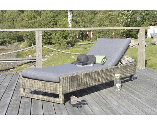 Flätad trädgårdsstol med dyna, hatt, skor och dryck på en träterrass