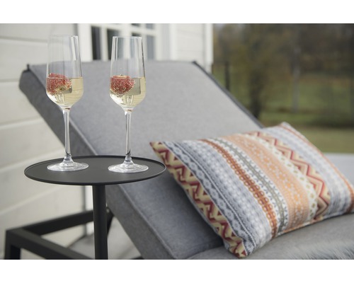 Två champagneglas med jordgubbar på sidobord bredvid solstol
