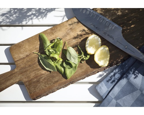 Skärbräda i trä med basilika, citron, kniv och kökshandduk