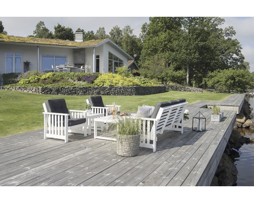 Sittgrupp på träterrass med hus i bakgrunden.