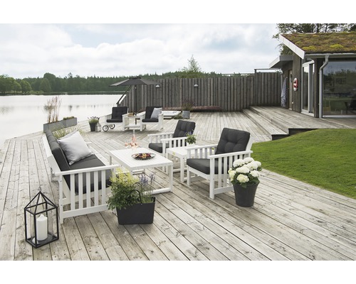 Ljus terrass med vita trädgårdsmöbler, kuddar och dekoration vid sjön