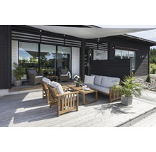 Terrass med trämöbler, solsegel och plantering framför ett modernt hus