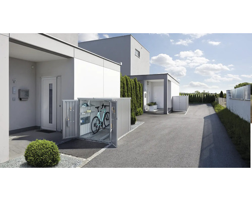 Cykelbox framför ett bostadshus med öppna dörrar, inuti står en cykel