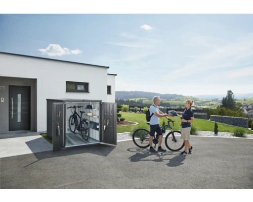 Cykelbox framför ett hus med två cyklar och två personer